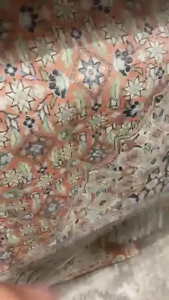 Motif d'un tapis à fond orangé avec étoiles et fleurs, vu de près